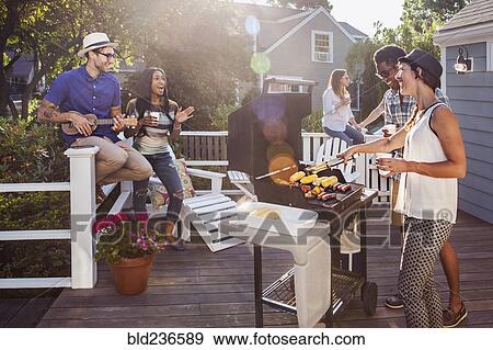 Stock Photo - Friends enjoying barbecue on patio. Fotosearch