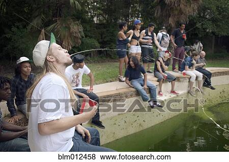 Stock Photo - Friends hanging out at edge of disused swimming pool. Fotosearch