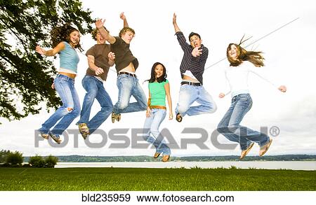 Stock Photo - Friends jumping for joy near river. Fotosearch