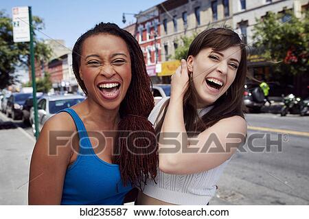 Stock Photo - Friends laughing on city sidewalk. Fotosearch
