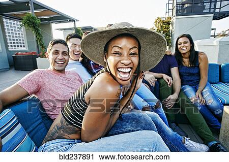 Friends laughing on rooftop sofa View Large Photo Image Stock Image - Friends laughing on rooftop sofa. Fotosearch