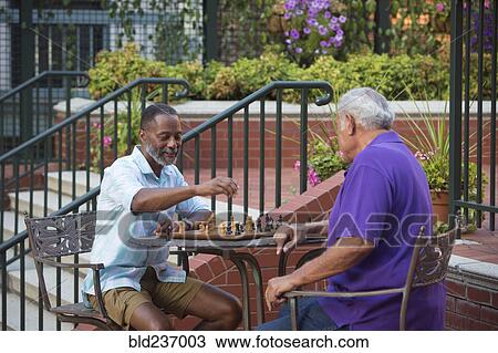 Stock Image - Friends playing chess in garden. Fotosearch