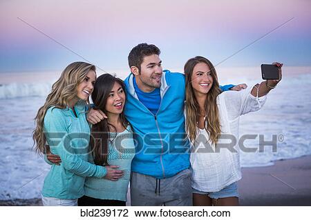 Friends posing for cell phone selfie on beach at sunset View Large Photo Image Stock Image - Friends posing for cell phone selfie on beach at sunset. Fotosearch