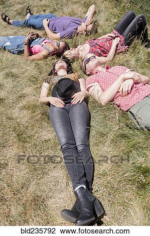 Stock Image - Friends relaxing in sunny grass field. Fotosearch