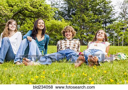 Stock Photo - Friends sitting and laying in grass. Fotosearch