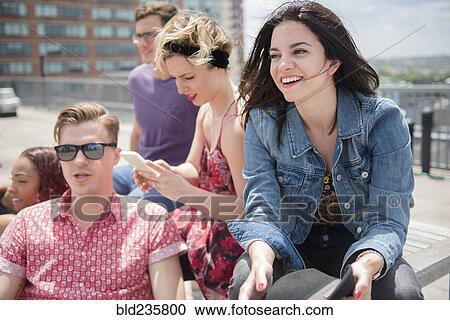 Stock Image - Friends sitting on bench in city. Fotosearch