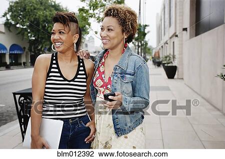 Stock Image - Friends standing together in city sidewalk. Fotosearch
