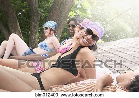 Stock Image - Friends sunbathing on roof. Fotosearch