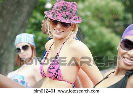 Stock Image - Friends sunbathing outdoors. Fotosearch