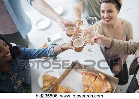 Friends toasting over box of pizza View Large Photo Image Stock Photograph - Friends toasting over box of pizza. Fotosearch