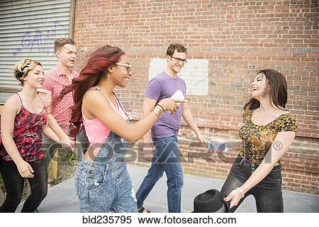 Stock Photography - Friends walking and laughing in city. Fotosearch