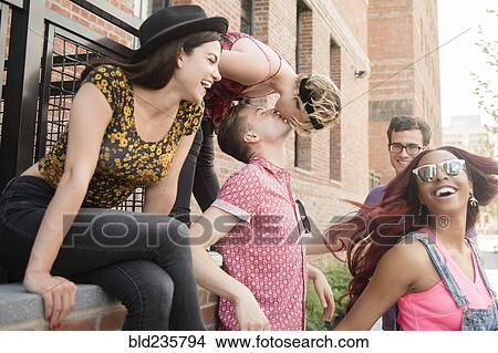 Picture - Friends watching couple kissing in city. Fotosearch