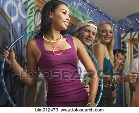 Friends watching woman holding hula hoop at party View Large Photo Image Stock Image - Friends watching woman holding hula hoop at party. Fotosearch