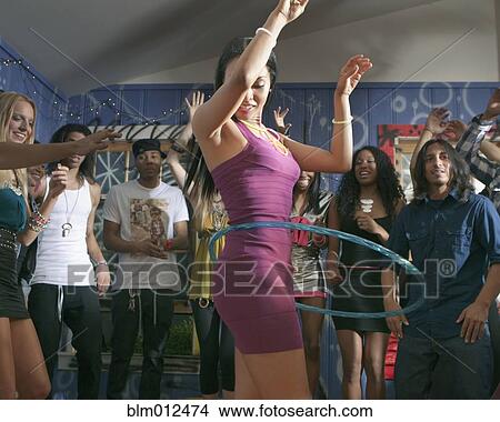 Picture - Friends watching woman using hula hoop at party. Fotosearch