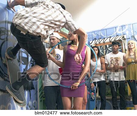 Stock Photo - Friends watching woman using hula hoop at party. Fotosearch