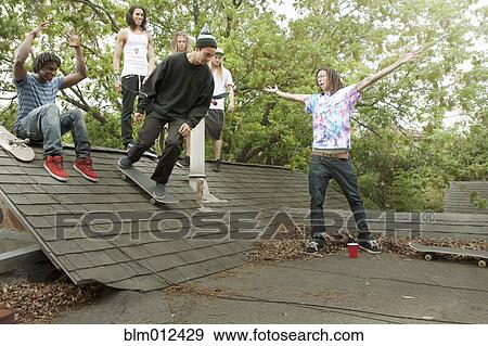 Stock Photo - Friends with skateboards hanging out on roof. Fotosearch