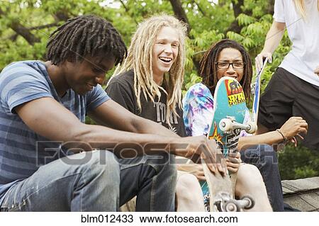 Stock Image - Friends with skateboards hanging out. Fotosearch