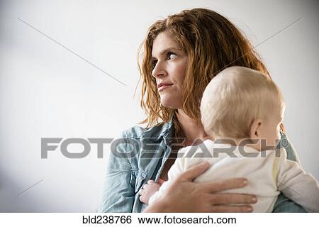 Frustrated Caucasian mother holding baby son View Large Photo Image Stock Photograph - Frustrated Caucasian mother holding baby son. Fotosearch