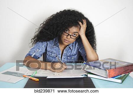 Stock Image - Frustrated Mixed Race teenage girl doing homework. Fotosearch