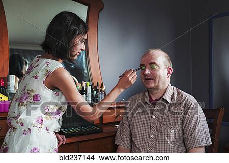 Picture - Girl applying makeup to eyes of father. Fotosearch