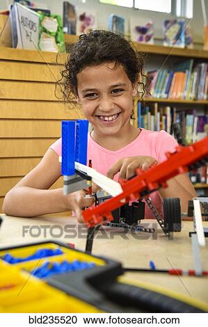 Stock Image - Girl assembling plastic blocks in library. Fotosearch