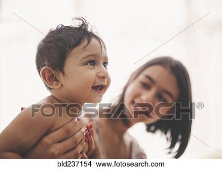 Girl holding smiling baby brother View Large Photo Image Picture - Girl holding smiling baby brother. Fotosearch