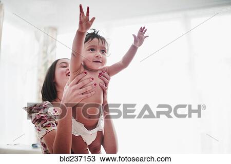 Stock Image - Girl lifting baby brother. Fotosearch