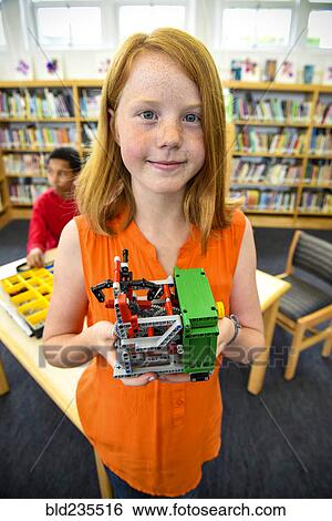 Stock Photograph - Girl posing with plastic blocks in library. Fotosearch
