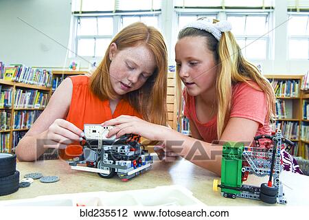 Stock Image - Girls assembling plastic blocks in library. Fotosearch