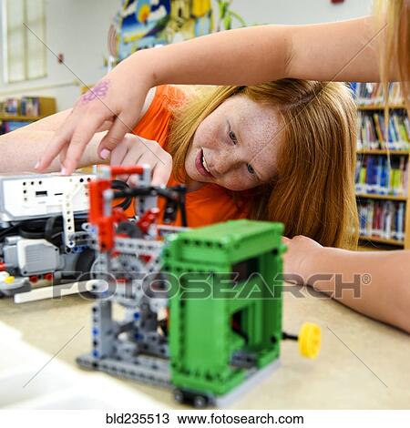 Stock Image - Girls assembling plastic blocks in library. Fotosearch