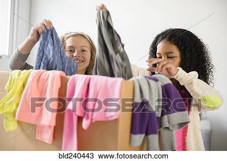 Girls examining box of clothing View Large Photo Image Stock Image - Girls examining box of clothing. Fotosearch