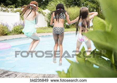 Girls jumping into swimming pool View Large Photo Image Stock Photo - Girls jumping into swimming pool. Fotosearch