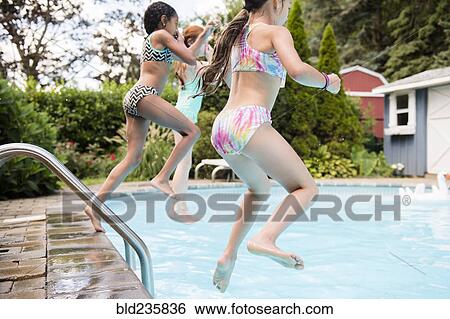 Stock Photograph - Girls jumping into swimming pool. Fotosearch
