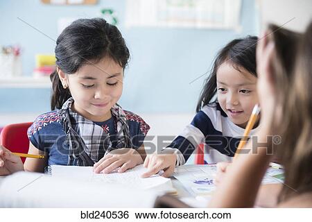 Girls reading notebook in classroom View Large Photo Image Stock Photograph - Girls reading notebook in classroom. Fotosearch