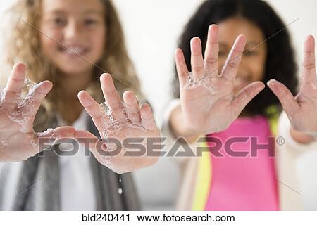 Stock Image - Girls showing palm of hands with soap suds. Fotosearch