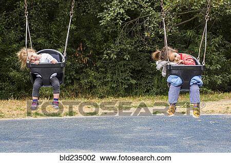 Girls sitting in still swings View Large Photo Image Stock Image - Girls sitting in still swings. Fotosearch
