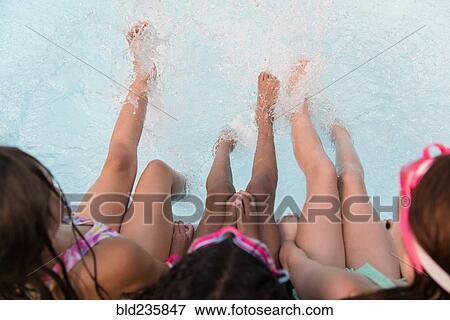 Stock Photo - Girls splashing feet in swimming pool. Fotosearch