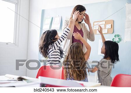 Girls surrounding teacher with headache in classroom View Large Photo Image Stock Image - Girls surrounding teacher with headache in classroom. Fotosearch