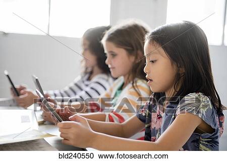 Girls using digital tablets in classroom View Large Photo Image Stock Image - Girls using digital tablets in classroom. Fotosearch