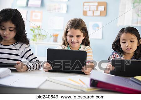 Stock Photo - Girls using digital tablets in classroom. Fotosearch