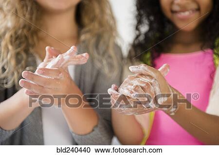 Stock Image - Girls washing hands with soap. Fotosearch