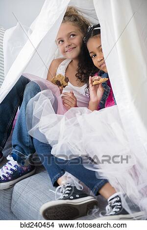Picture - Girls wearing tutus in blanket fort on sofa. Fotosearch
