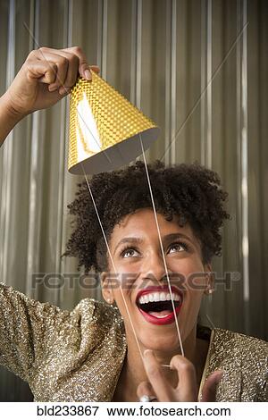 Stock Photo - Glamorous Black woman holding party hat. Fotosearch