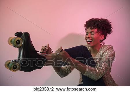 Stock Image - Glamorous Black woman tying roller skate. Fotosearch