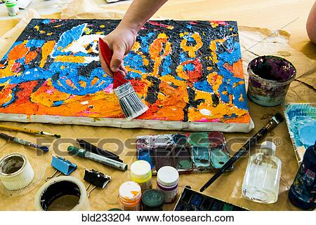 Picture - Hand brushing paintbrush over canvas painting. Fotosearch