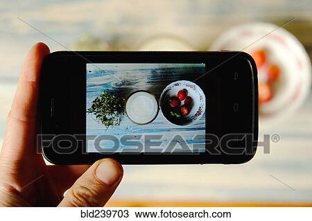 Stock Image - Hand of Caucasian woman photographing food. Fotosearch