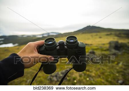 Stock Photo - Hand of man holding binoculars outdoors. Fotosearch