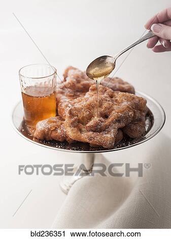 Stock Image - Hand spooning sauce over dessert. Fotosearch
