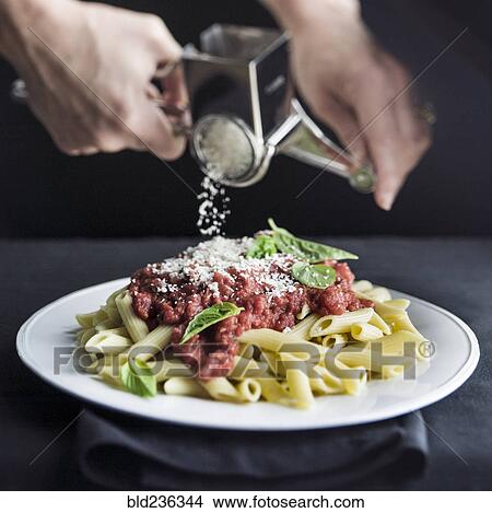 Hands grating parmesan cheese on penne pasta View Large Photo Image Picture - Hands grating parmesan cheese on penne pasta. Fotosearch