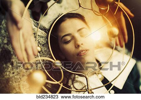Stock Image - Hands holding metal circle over face of Caucasian woman. Fotosearch